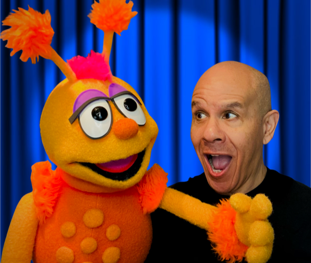 image of a bald man and a giant yello puppet weraing an orange polka dot sweater