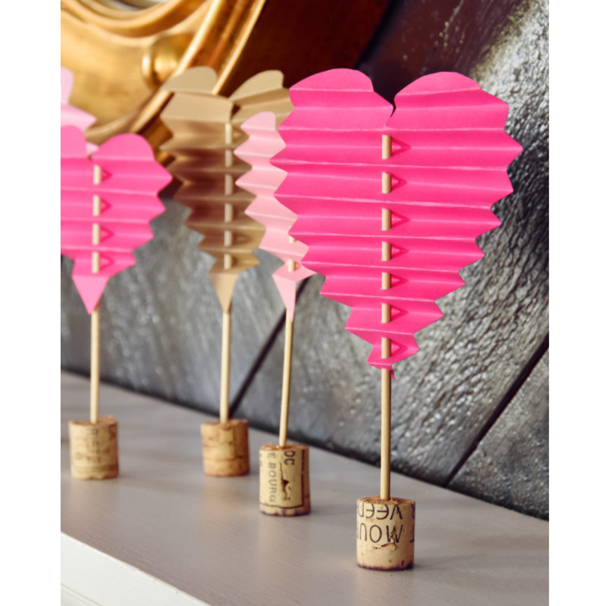 image of 4 folded paper hearts with a small dowel running through them and attached to a base made from a cork.