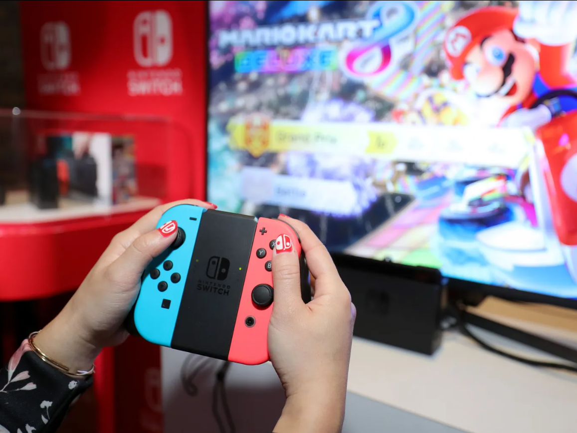 Hands holding a Nintendo Switch controller as they play Mario Kart